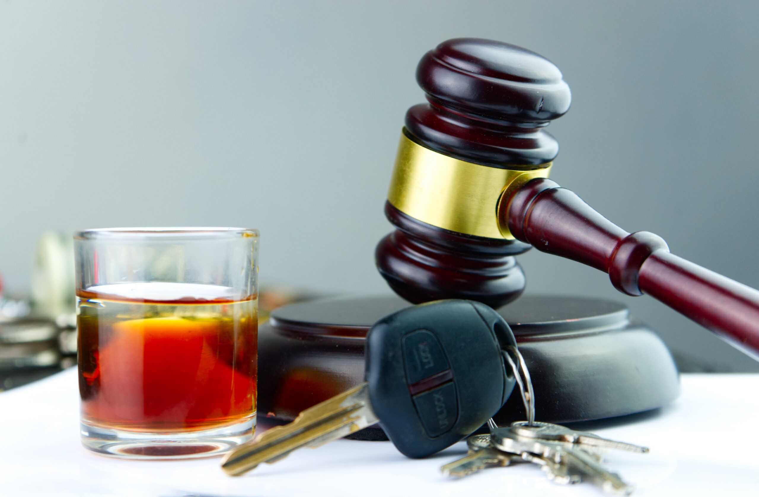 A set of keys and a glass filled with an alcoholic beverage sit in front of a justice gavel on a table. Contact our experienced DUI lawyers in Oklahoma for a strong legal representative